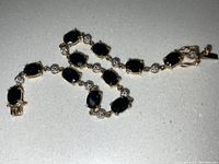 Full length view of bracelet showing alternating oval sapphire stones and round diamond accent links