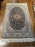 Full view of rectangular Persian carpet laid flat on wood floor showing overall pattern and color balance