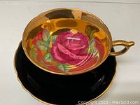 Top-down view of cup interior showing red rose motif and saucer beneath