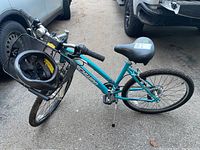 Full side view of teal Schwinn bike with front basket holding helmet