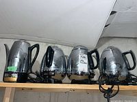 Four chrome electric percolators on wooden shelf