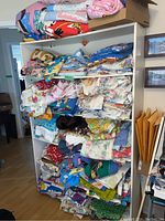 Wide view of six shelves filled with assorted folded fabrics showing a variety of colors and patterns.