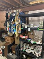 Wide shot of shirts hanging on rack above shelving units in unfinished basement
