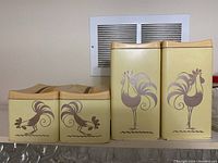 Front view of four canisters with rooster designs (two tall, two short)