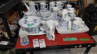 Full overview on red table showing platter, covered serving dish, creamer, mugs, rectangular dishes, teapot, sauce pot