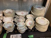 Overview of Noritake dishes on shelf showing stacks of plates, cups, saucers, sugar bowl and creamer