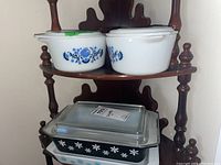 Two round Luna-style casserole bowls with lids on top shelf; below, one black Snowflake space saver dish and one white Snowflake dish stacked with glass lid on black dish