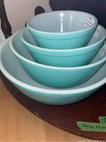 Four nested turquoise glass mixing bowls with white interiors, etched Pyrex labels visible