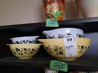 Four Pyrex mixing bowls displayed on shelf: two yellow on bottom row, two white on top row, showing overall set and pattern.
