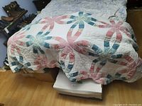 Overall view of quilt draped over bed showing pattern, colors and size.