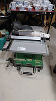 Table saw on green wheeled base with aluminum table surface and fence attached, view showing overall condition.