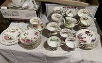 Overall view of 12 teacups, 12 saucers, side plate and bread plate arranged on table