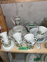 Overview of coffee pot, teapot, cups, saucers, plates and serving bowl on shelf