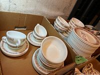 Two handled soup bowls on a stack of Pyrex plates, small border bowls and plain oval dishes