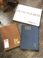 Three books on floor: Peanuts Jubilee, Norman Rockwell Illustrator, Sherlock Holmes Scrap Book.