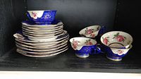 Stacked set showing 6 luncheon plates with 6 saucers and 6 teacups, blue and white porcelain with floral and gold details