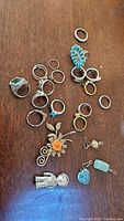 Multiple rings, brooches, and pendants on wooden table, showcasing size and variety.