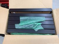 Box containing several black IKEA picture frames wrapped in bubble wrap.