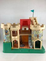 Full front view of the vintage Fisher Price Fairy Castle toy showing two stone-patterned towers, central red roof entrance, and green base.