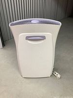 Front view of the large white tower air purifier with a curved top vent, white body, and grey handle.