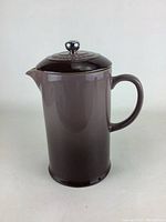 Full view of brown stoneware coffee pot with handle and lid with chrome knob.