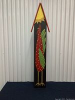 Front view of the hand painted tall decorative chicken bird house, showing large red chicken with green wings and yellow sun, red peaked roof