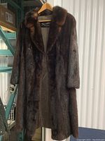 Full view of a vintage mink fur coat hanging on a wooden hanger showing length and texture.