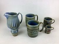 Front view of jug, large mugs, small mugs, and shaker showing design and condition