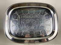 Top view of vintage metal bar tray with etched cocktail recipes and bar scene image.
