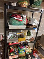 Shelf containing various boxes and bags filled with Christmas ornaments and decorations, including boxed glass ornaments and seasonal storage containers.