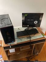 Dell Inspiron desktop tower, monitor, keyboard, mouse set up on wooden stand with power surge protector beneath