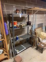 Full view of the metal shelving unit in basement, displaying four shelves and rust on top shelf.