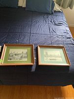 Pair of two framed wall art photos on a blue surface, showing the overall appearance and size relative to the bed.