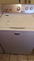 Front view of white Maytag top load washer with closed lid.