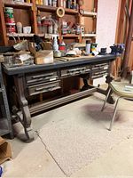 Work table with five drawers and a cluttered top in a basement setting.