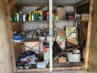Full view of garden care items on wooden shelves showing various spray bottles, jars, containers, and tools, some in boxes and containers.