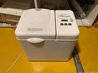Front and top view of white West Bend bread maker showing dual lid with control panel and handle.