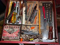 Full view showing vintage hand tools, hardware, and Sentinel First Aid Kit in metal box