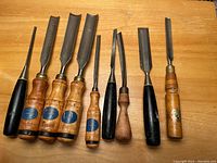 Ten tools laid out on a wooden surface showing handles and blades