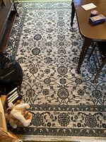 Full view of the modern-style floral area rug under a table with surrounding items showing overall condition and size.