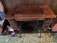 Full front view of the sewing machine cabinet with drawers and treadle base visible