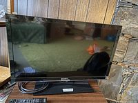 Front view of Sony KDL-32EX340 TV showing screen and stand with cables and remote control placed in front.