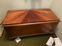 Full view of the vintage wooden chest with sunburst panel top and an extra lock mounted on a wooden block.