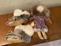 Photo showing the pair of vintage fur-lined boots and the vintage doll laid on a wooden surface.