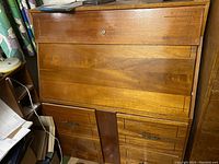 Front view of the vintage wooden secretary desk showing the drop-front closed and the drawer and cabinet layout.