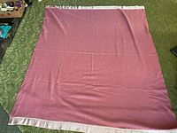 Full view of the vintage wool blanket spread out, showing muted rose color and satin trim on edges.