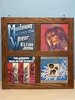 Four vintage album cover art pieces mounted in a single wood frame: Madman Across the Water by Elton John, Sussudio, The Arrows Wild in the Streets, and The Jackson 5 Christmas Album.