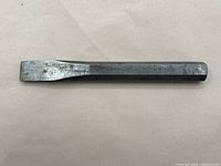 Full view of vintage metal chisel with a hexagonal shaft and flat blade end.