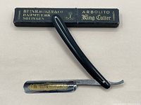 Straight razor folded next to its original box with clear brand and model markings.