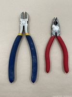 Two wire cutters with blue and red handles, placed against a neutral background.